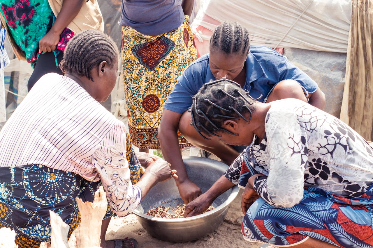 Group of women collaboratively sorting beans outdoors, showcasing cultural richness.