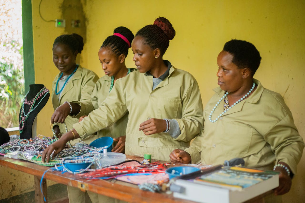 Four women working together on beaded jewelry in a workshop.